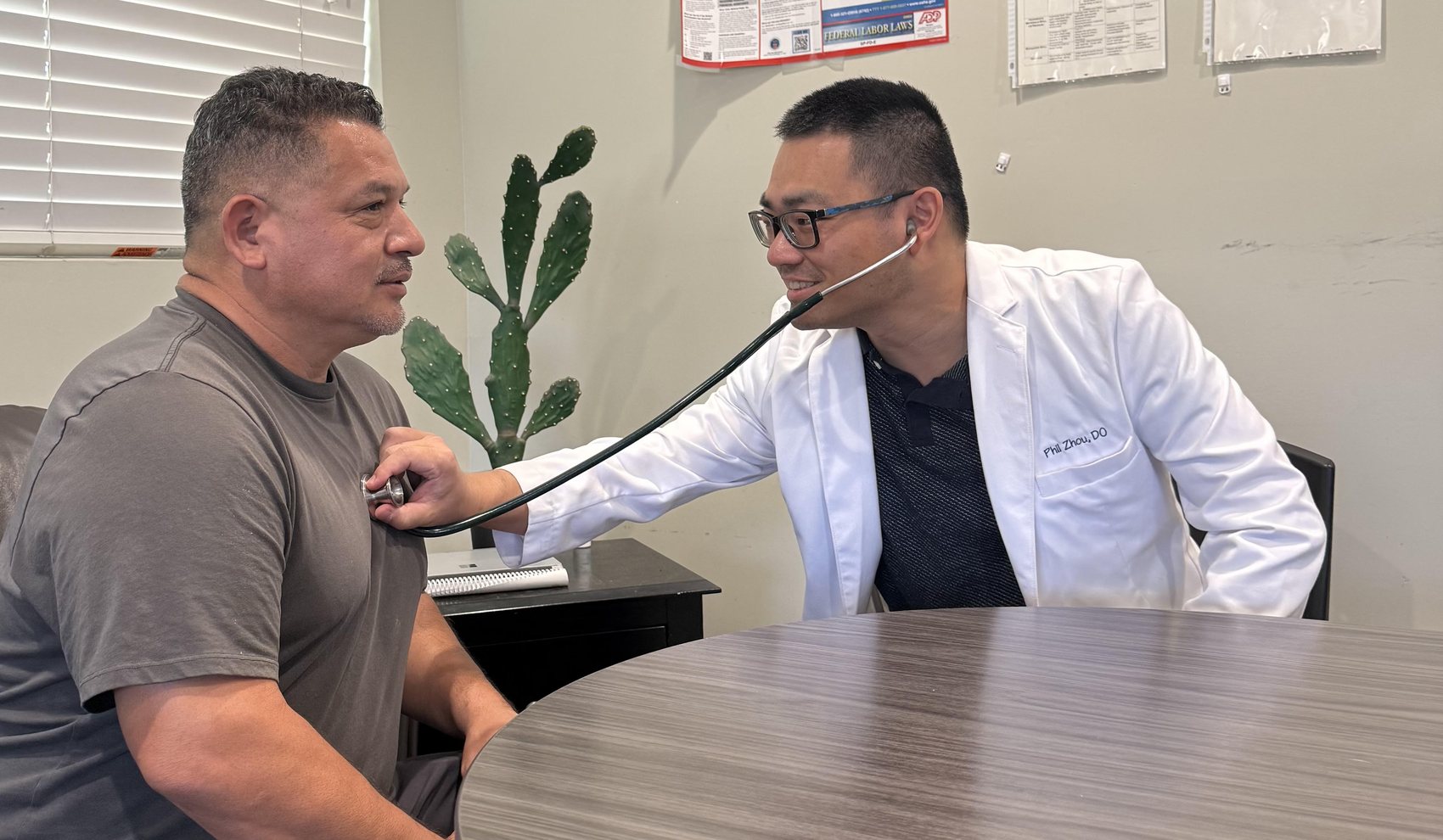 Phil Zhou, DO listening to a patient’s heart during an office visit